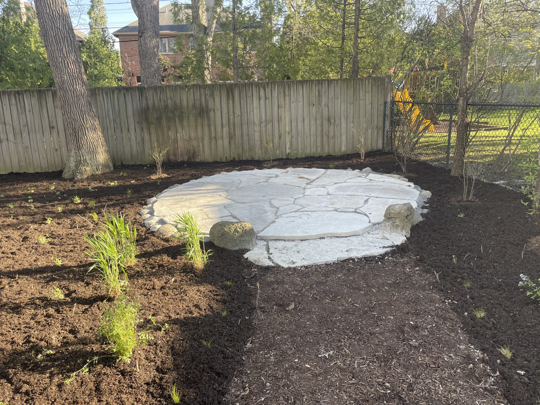 Circular flagstone patio set into a freshly planted bed