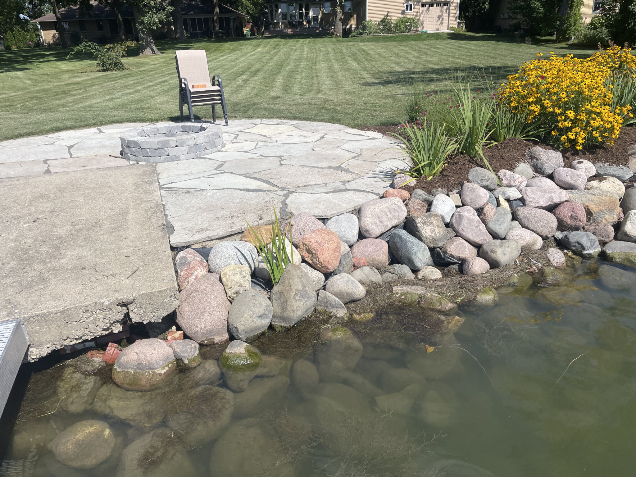 Flagstone patio meeting a boulder edged pond