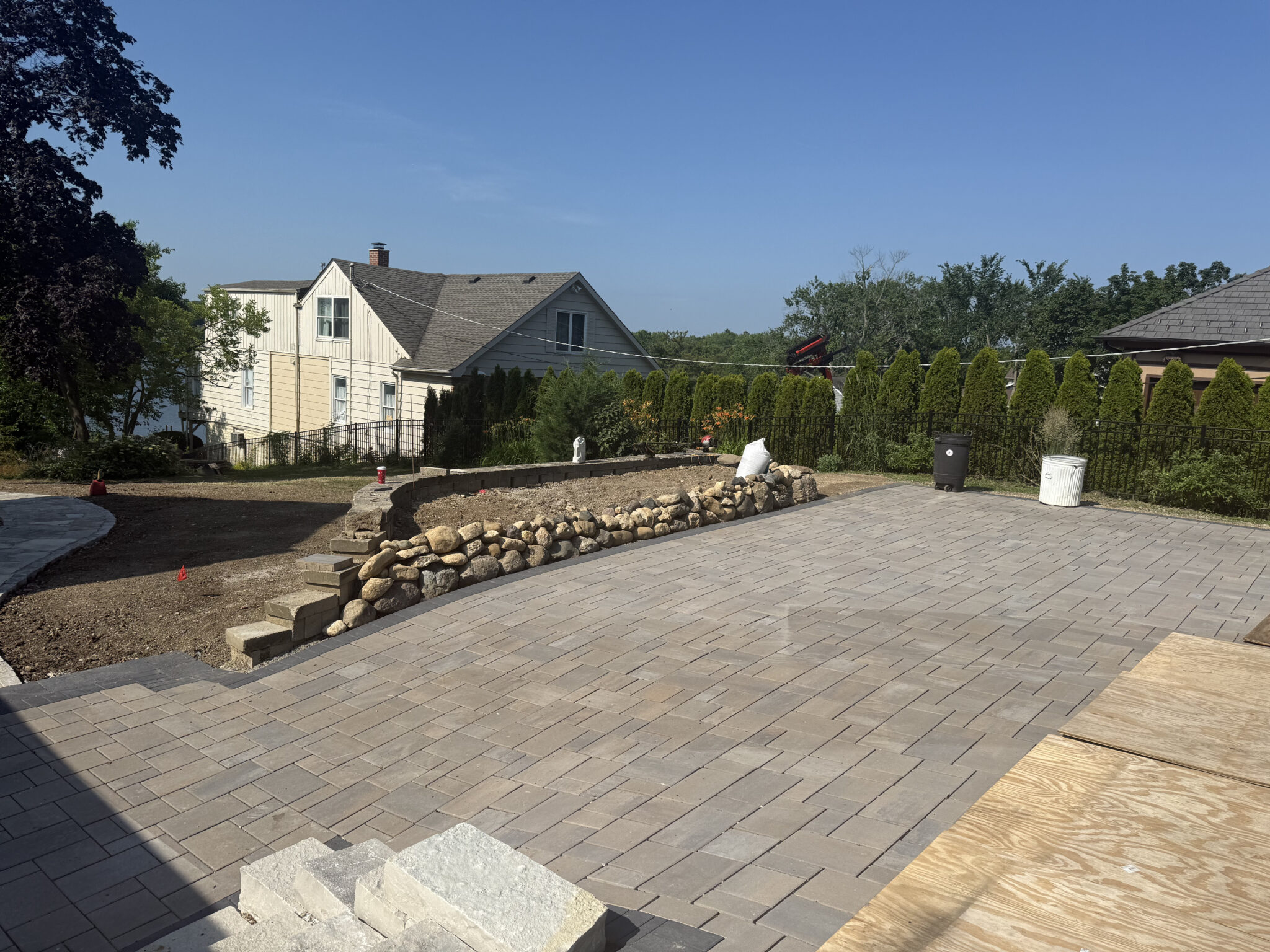 A finished paver patio and stone retaining wall on a residential property